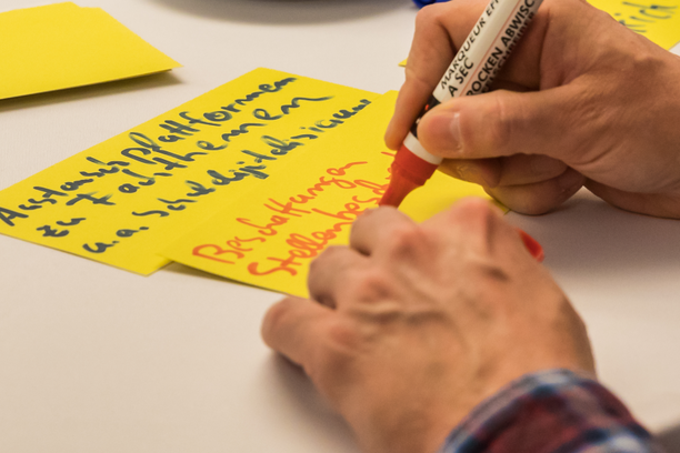 zwei Hände, schreibend auf gelbe Ideenkarten